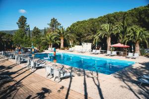 une grande piscine avec des chaises et des palmiers dans l'établissement Casa Dei Prati Camping Village, à Lacona