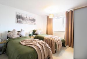 艾爾斯伯里的住宿－Virexxa Aylesbury Centre - Deluxe Suite - 3Bed House with Free Parking，一间卧室设有两张绿色的床和窗户
