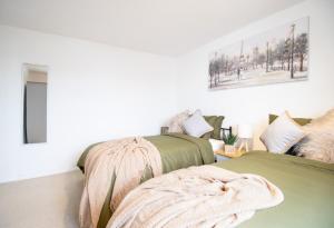 una camera con 2 letti verdi e una coperta di Virexxa Aylesbury Centre - Deluxe Suite - 3Bed House with Free Parking ad Aylesbury