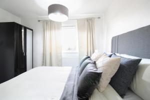 Virexxa Aylesbury Centre - Deluxe Suite - 3Bed House with Free Parking في آيْلسبري: غرفة نوم بسرير ابيض ونافذة