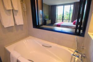 a bath tub in a bathroom with a mirror at The Zign Hotel in Pattaya North