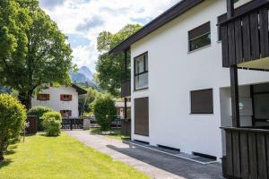une maison blanche avec des fenêtres noires et une allée. dans l'établissement Alpennest, à Garmisch-Partenkirchen