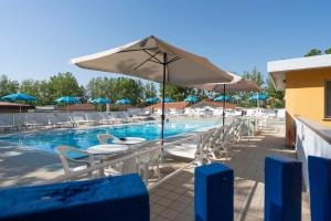 a pool with tables and chairs and an umbrella at VMBabyhotel & Residence Parador in Cesenatico
