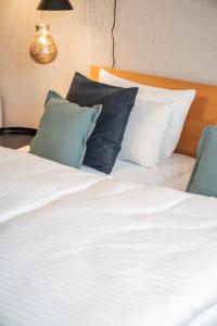 una camera da letto con letto, lenzuola e cuscini bianchi di Apartments Leopold Ferdinand a Sankt Stefan im Lavanttal