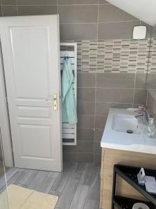 a bathroom with a sink and a white door at la grange à Emile in Dambach-la-Ville