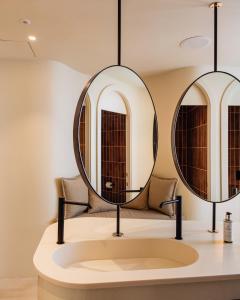 a bathroom with two mirrors on a sink at Pacha Hotel in Ibiza Town