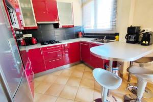 - une petite cuisine avec des placards rouges et une table blanche dans l'établissement LE PRADET 50m de la plage T2 tout confort LESCLESDENICOLE, au Pradet