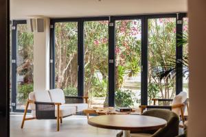 ein Wohnzimmer mit großen Fenstern, Tischen und Stühlen in der Unterkunft El Hotel Pacha in Ibiza-Stadt