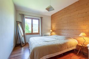 1 dormitorio con pared de madera, cama y ventana en La Forêt de Ventron en Ventron
