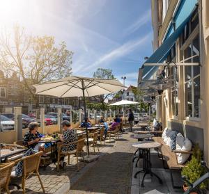 een groep mensen die met een paraplu aan tafel zitten bij Nr 19 Bed and Bubbels in Middelburg