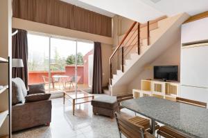 a living room with a staircase and a table and chairs at PARK SEDO Aparthotel in Rub&iacute;