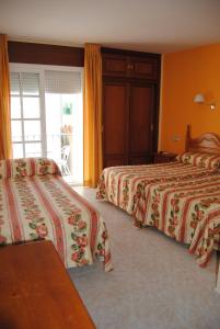 a hotel room with two beds and a balcony at Hostal Italia in Fuengirola