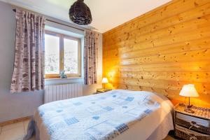 1 dormitorio con pared de madera, 1 cama y 2 lámparas en Les Pistes de Ventron, en Ventron