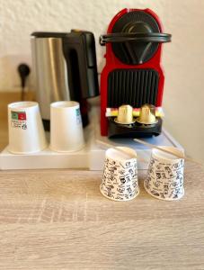 a coffee maker and four cups on a counter at Hotel Les Pavillons Du Golfe in Favone +24 photos