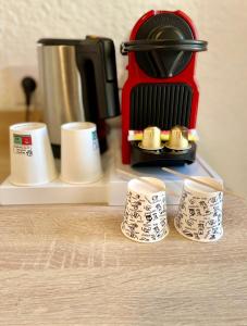a coffee maker and four cups on a counter at Hotel Les Pavillons Du Golfe in Favone