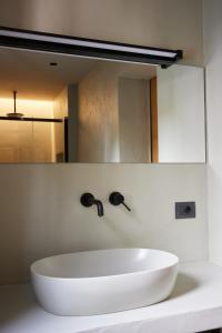 lavabo blanco en el baño con espejo en Mima Aparthotel Boutique & Spa, en Milano Marittima