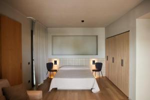 um quarto com uma grande cama branca e 2 cadeiras em Mima Aparthotel Boutique & Spa em Milano Marittima