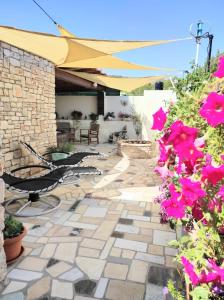 維斯的住宿－HOLIDAY HOME ZLOPOJE，庭院里种着粉红色的鲜花,配有遮阳伞