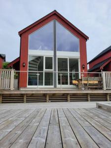 a house with a large window on a wooden deck at Waterfront Ballstad, Lofoten in Ballstad