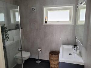 a bathroom with a toilet and a sink and a window at Waterfront Ballstad, Lofoten in Ballstad