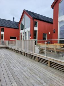 un edificio rojo con una terraza de madera al lado en Waterfront Suite l Ballstad l Lofoten l Norway, en Ballstad