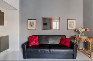 a black leather couch with red pillows in a living room at VIA VENETO SUITE 529 in Rome