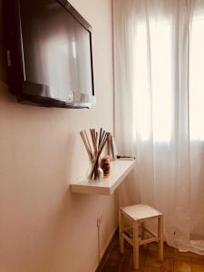 un estante en una pared con TV y un taburete en Puerto Escondido, en Castro di Lecce