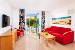 een woonkamer met een rode bank en een tafel bij MUR Bungalows Parque Romantico in Playa del Inglés