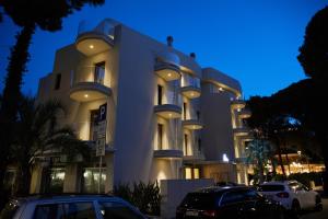 a large white building with cars parked in front of it at Mima Aparthotel Boutique & Spa in Milano Marittima