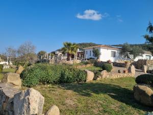 einen Garten mit Felsen und ein Haus im Hintergrund in der Unterkunft La Quercia della Gallura in Luogosanto