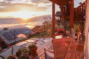 einen Balkon mit einem Tisch und Stühlen sowie einem Sonnenuntergang in der Unterkunft Die Mirnockhütte in Ferndorf