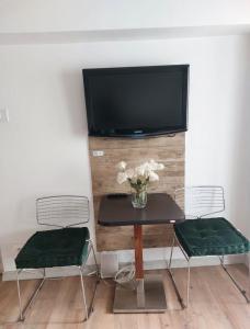 2 sillas y mesa con TV en la pared en Piata Victoriei Kiseleff Studio Apartment, en Bucarest