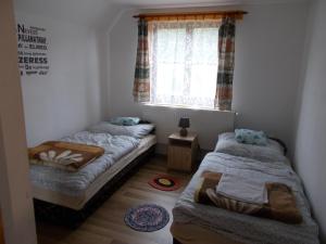 two beds in a room with a window at Boltíves Vendégház in Sajógalgóc