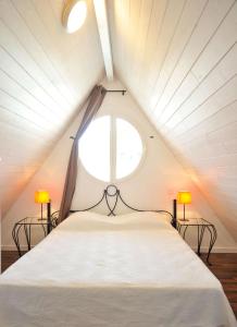 1 dormitorio con 1 cama blanca grande y 2 lámparas en Lagrange Vacances - Résidence Jardin Mauresque, en Arcachon