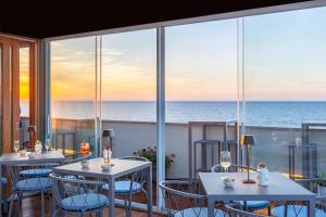 ein Restaurant mit Tischen und Stühlen und Meerblick in der Unterkunft Residence La Gancia in Trapani