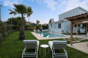 a backyard with a pool and chairs and a palm tree at Villa Elora Platanias in Platanias