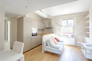 een woonkamer met een witte bank en een keuken bij SAINT DOMINIQUE PARIS 7 - BEST PLACE - BAIL MOBILITE in Parijs