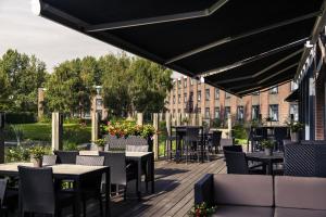 un patio avec des tables et des chaises et un bâtiment dans l'établissement Mercure Hotel Amsterdam West, à Amsterdam