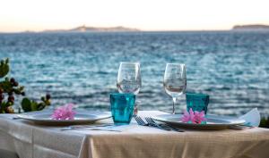 a table with two plates and glasses on the water at Hotel L'Oleandro in Villasimius