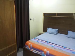 un letto con testiera in legno in una stanza di Résidence Lynda Prestige a Ouagadougou
