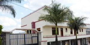 Macchiato Suites في كيغالي: بيت ابيض امامه اشجار النخيل