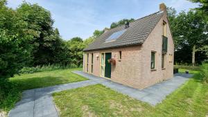 a brick house with a green door on a yard at Recreatiewoning Maas en Waal 72 in Ewijk