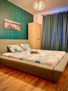 a bed in a bedroom with a green wall at Arcadia Apartament Mamaia Nord in Mamaia Nord