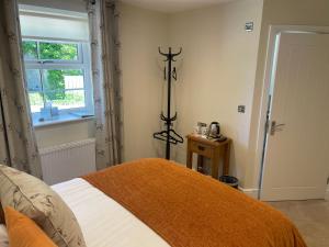 sypialnia z łóżkiem z pomarańczowym kocem i oknem w obiekcie The Black Bull Inn w mieście Lowick