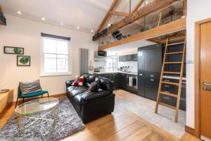 a living room with a black leather couch and a kitchen at My Unique Place - St Peters Mews in St. Albans