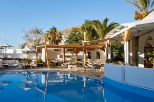 einen Pool in einem Resort mit Tischen und Stühlen in der Unterkunft Hermes Hotel in Kamari