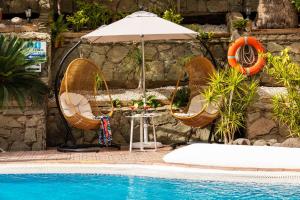 two chairs and an umbrella next to a pool at MUR Neptuno Gran Canaria - Adults Only in Playa del Ingles