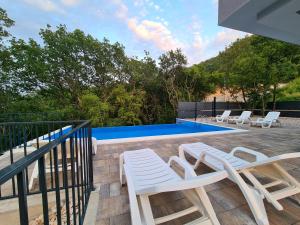 a patio with two white chairs and a pool at Holiday Resort Bevel in Mostar