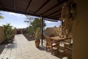 an outdoor patio with a wooden table and chairs at BEACH FRONT GRANILLO - ocean view, garden, bright and comfortable, Wi-Fi in Costa Calma