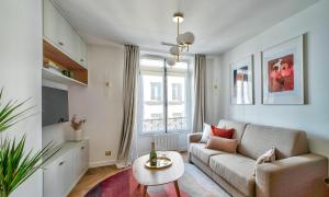 ein Wohnzimmer mit einem Sofa und einem Tisch in der Unterkunft Sompteux appartement proche de L'Opéra in Paris